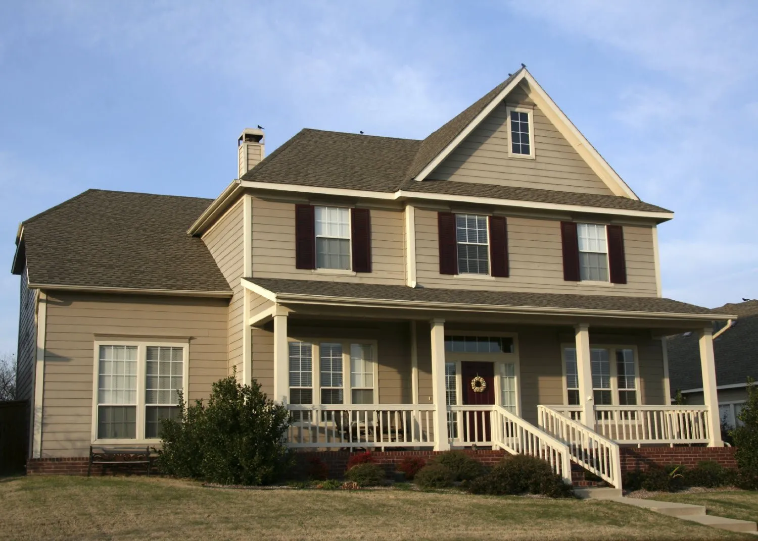 Large two-story home with front porch and new gray-beige vinyl siding.